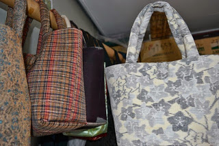 布製の手提げバッグが何点も棒にかけて吊るされている様子の写真