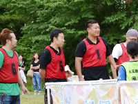 赤いビブスを付けた男性4名が1列に並んでいる写真