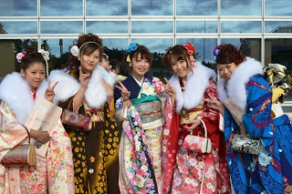 色とりどりの振袖を着た5名の新成人の女性たちが笑顔で写っている写真