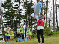 赤いビブスの男性がシャチのフロートを上にあげ喜んでいる様子を写した写真