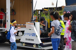 観客が見守る中、男の子が乗り物にのっている様子を写した写真