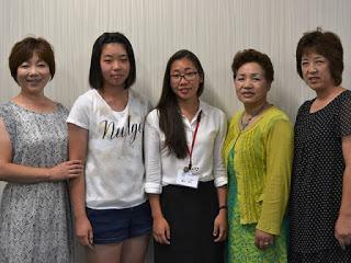 亀山さんを中心に左右2名ずつ女性が並んで記念撮影をしている写真
