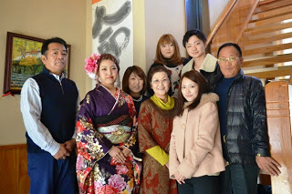 成人式に参加した振り袖姿の女性が、家族とともに室内の階段前で記念撮影をしている写真