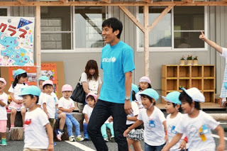 園庭で長谷部選手と園児たちが笑顔で遊んでいる写真