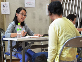 女性2名が向かい合って長机に座り悩み相談をしている様子を写した写真