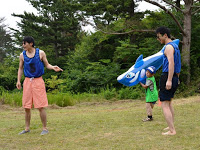 男性2名が立っている横で男の子がシャチのフロートを取って喜んでいる写真