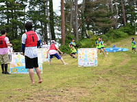 屋外の広場で2チームが水風船を相手チーム当てようと試合をしている様子を写した写真