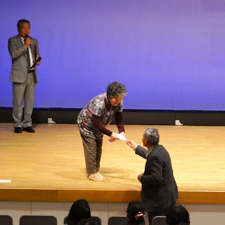 舞台の女性におひねりを渡している男性の写真