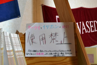 手書きで「携帯とイヤホンは絶対使用禁止」と大きく書かれた注意書きの貼り紙が掲げられている写真