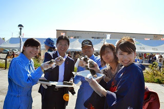 巻き寿司を手にした男女5人が笑顔でカメラに向かってポーズをとっている写真