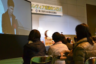 大きなモニターに男性が映っている写真