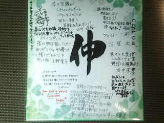 中央に力強く「伸」と書かれ、周りに多くの人からの感謝や応援の言葉が寄せ書きされている、緑のクローバー模様の色紙の写真
