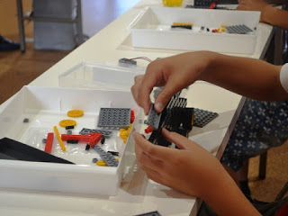 白いトレイにレゴブロックのパーツが入っており、黒やグレーのレゴブロックを使って集中して組み立て作業をしている子どもの手元を写した写真