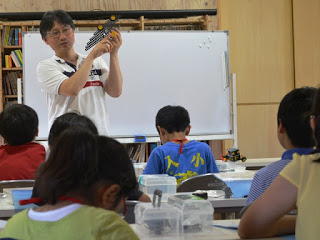 講師の猪狩憲一さんがロボットを手に持ち子供たちに見せている様子を写した写真