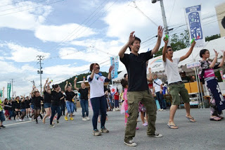 男女混合のグループが両手を高く上げながら笑顔で踊っている写真