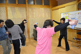 ダンベルを持った女性たちが腕を横に大きく広げたり振ったりしており、笑顔も見られる写真