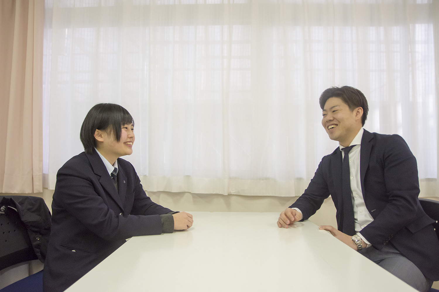 三浦千裕さんと佐藤陽さんが向かい合って座り、笑顔で会話をしている様子の写真