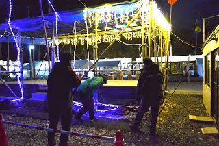 暗くなってから舞台にイルミネーションを飾っている3名の関係者の写真