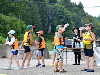 陸に戻ったこどもたちがペットボトルの飲み物を飲みながら休憩している写真