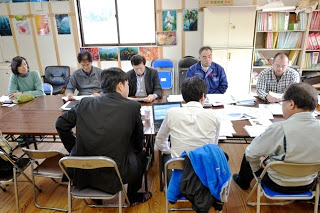 長机に向かい合わせで座っている関係者の方が話し合いをしている写真