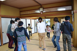 広い和室で子どもと大人が一緒に元気に体を動かしてリトミックを楽しんでいる写真