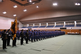 高い天井と観覧席のあるベイサイドアリーナの会場で、制服を着た大勢の人々が整列している出初式の様子の写真