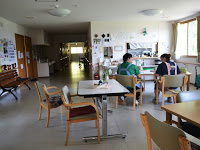 部屋の中テーブルと椅子のセットが複数置かれ、その一つに二人の女性が横並びに座っている様子を写した写真