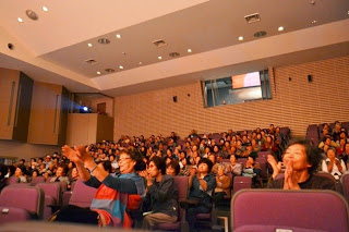 舞台を見ている観客が舞台に向かって拍手をしている様子の写真