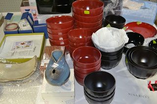 たくさんの赤と黒の椀が積み重ねられ、青い花瓶や皿が並んでいるフリーマーケットブースの写真