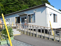 白い外壁の平屋建ての建物が写っており、玄関へと続く手すり付きのスロープが設置されている様子を示した写真