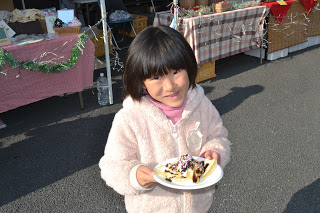 販売ブースの前でミニクレープが乗った紙皿を持っている女の子の写真