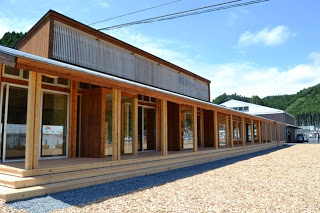 柱が等間隔に並び、広い木製デッキが建物全体に渡って伸びていている木材をふんだんに使用されている南三陸ポータルセンターの外観写真