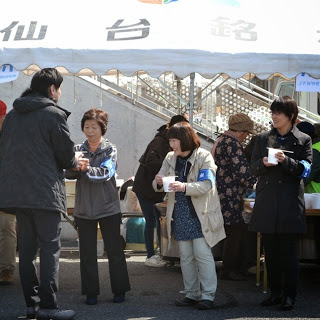 外に出た人たちに1列に並んでテントの前で汁物を配っている人達の写真