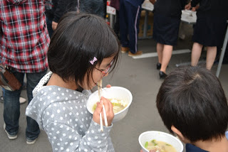 子どもたちが器に入った汁物を箸で食べている様子を間近から写した写真