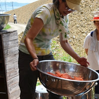 女性が赤く染まった羊毛が入った大きなステンレスのボウルを両手で持ちあげている写真