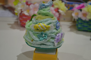 薄い緑色の毛糸で作ったツリーにカラフルなリボンや花が飾られた卓上ミニツリーの写真