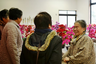 数人の来場者が三浦敏子さんと笑顔で会話している様子が写っている写真