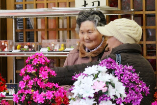 濃いピンク色のシルクフラワーの前に2人の女性が立ち止まり鑑賞している様子の写真