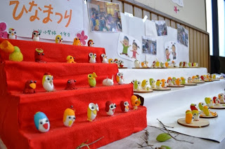 「ひなまつり」と書かれた紙の下に、子どもたちが作ったとみられる小鳥の形の人形が赤い段に飾られている写真