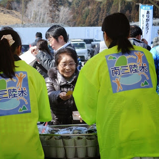 汁物を配るスタッフの後方から受け取る女性を写した写真