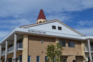 赤い屋根の時計塔が特徴的な南三陸町立戸倉小学校の校舎を、下から見上げるように撮影した外観の写真