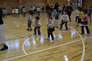 子どもたちが軽くかがみながら元気に体を動かしてダンスの練習をしている様子の写真