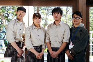 店内で3人の制服を着たスタッフと山田さんが横一列に並んで立っている写真