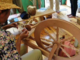 木製の糸車を使って手作業で糸を紡いでいる様子を写した糸紡ぎの写真