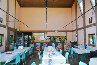 天井が高く明るく広い店内に、4人掛けのテーブルと水色の椅子が並べられているレストラン内の写真