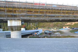 工事中の高架橋の下に重機や作業車両が見える状態で、建設現場の全体が写された写真