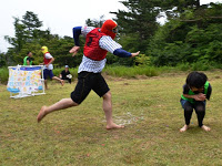 赤いビブスをつけた男性が中腰になっている男の子に走りながら向かっている写真