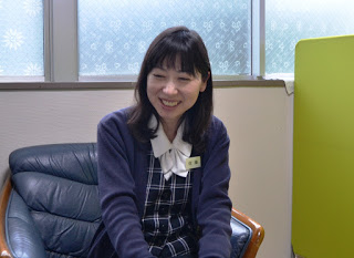 応接椅子に座った佐藤洋子さんが、笑顔で会話をしている様子の写真