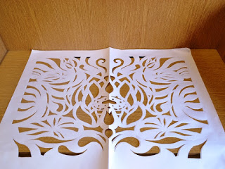 机に置かれた大きな白い紙の蓮の花をかたどられた切り絵の写真