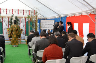 テントの中に置かれた祭壇の前で神事が行われており、椅子に座った出席者たちが頭を下げている様子の写真